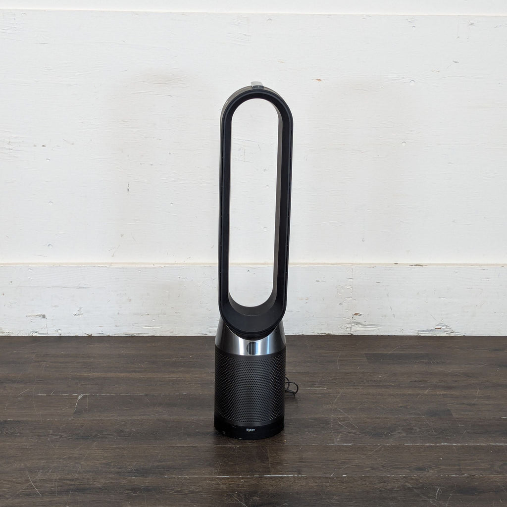 2. Front view of a Dyson bladeless fan and air purifier on a dark wooden floor, against a white wall.