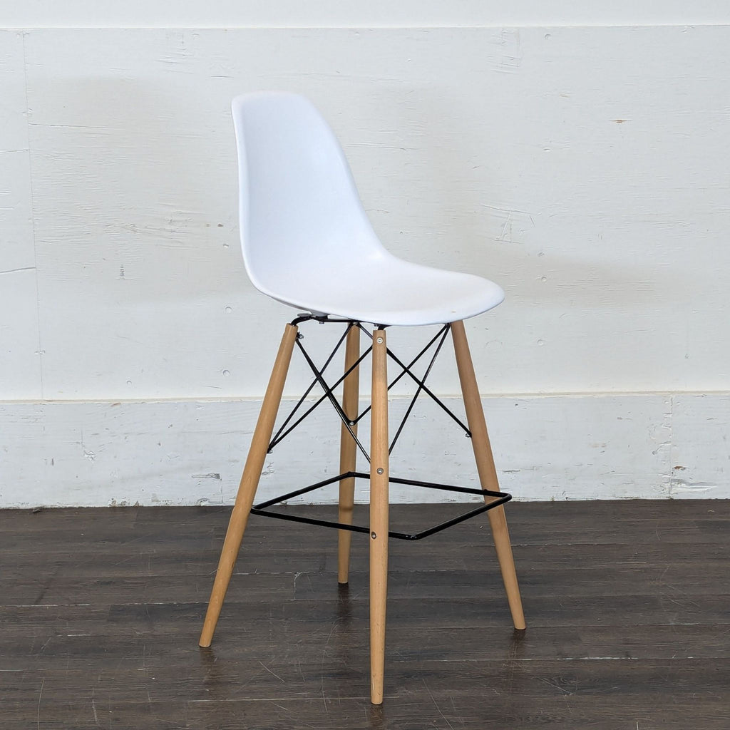 - Side view of a white plastic dining chair with natural wood legs and black metal accents on a wooden floor.