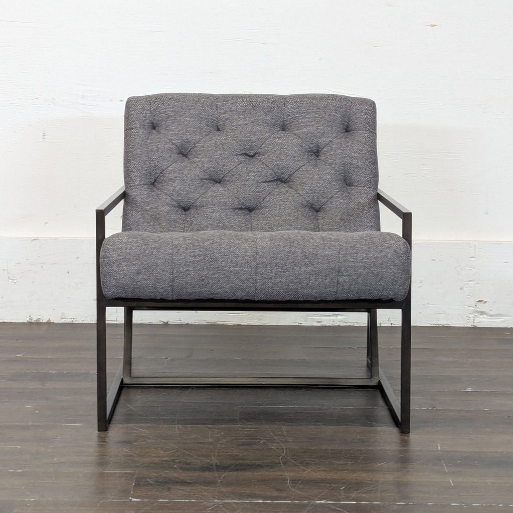 3. Single Alder & Tweed lounge chair with button-tufted grey fabric and black metal frame on wood floor.
