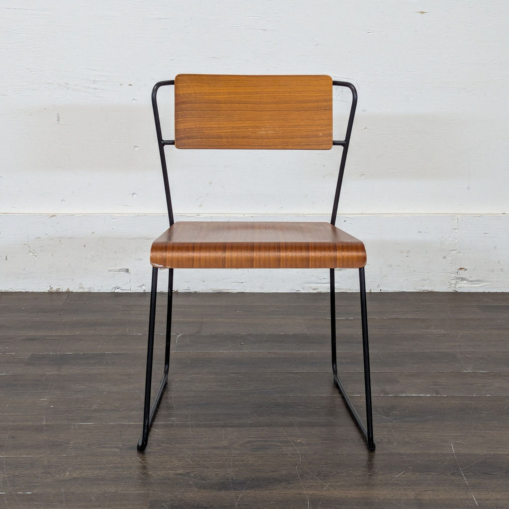 2. Sleek m.a.d. Furniture Design dining chair with bent wood seat and backrest, black metal legs, on wood floor.