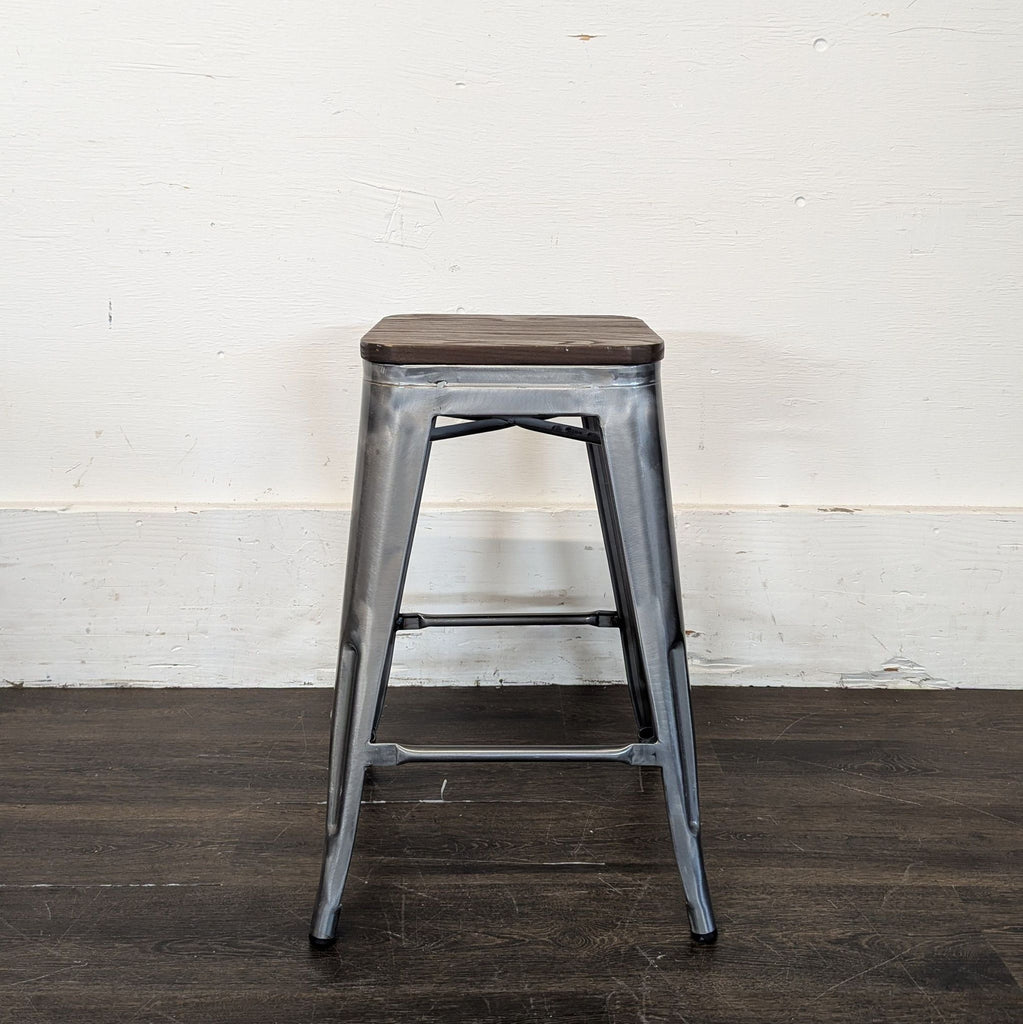 2. Industrial-style metal stool with a square dark wood top, seen against a white wall and wooden floor.