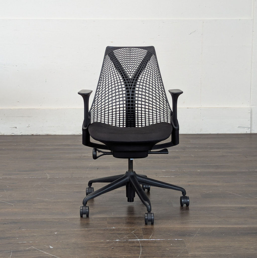 2. Front view of a Herman Miller task chair in black with mesh-style back and ergonomic armrests on wooden floor.