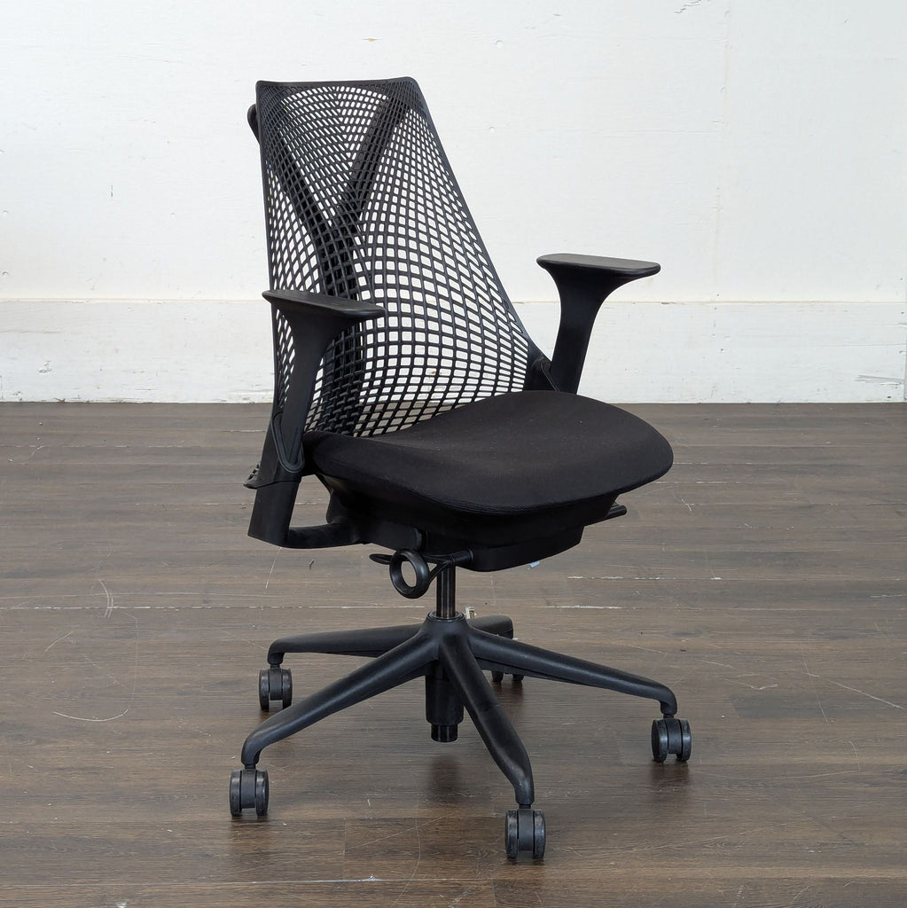 3. Angled side view of a black Herman Miller mesh-back ergonomic office chair on caster wheels with armrests.