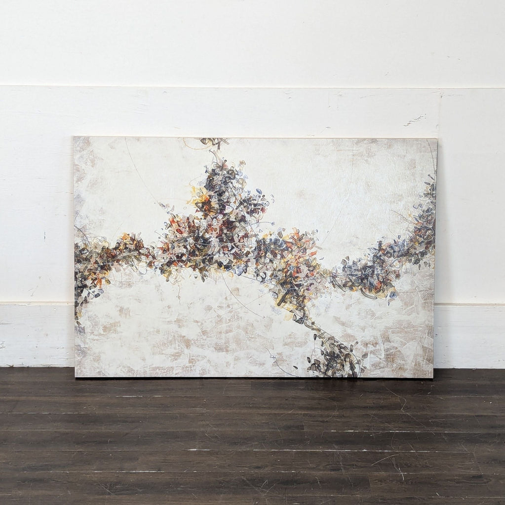 2. Large abstract artwork with textured beige surface and dark, colorful central design, leaning against a white wall.
