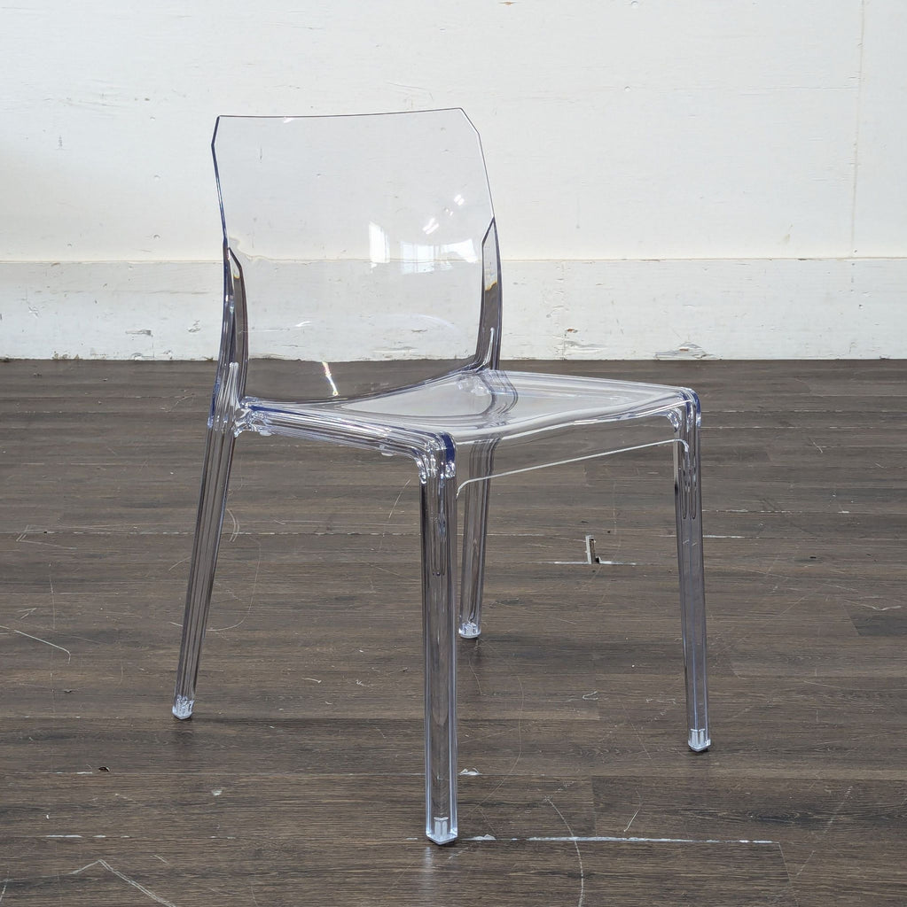 3. Side view of a clear CB2 dining chair showing its contemporary, minimalist acrylic frame on wood flooring.