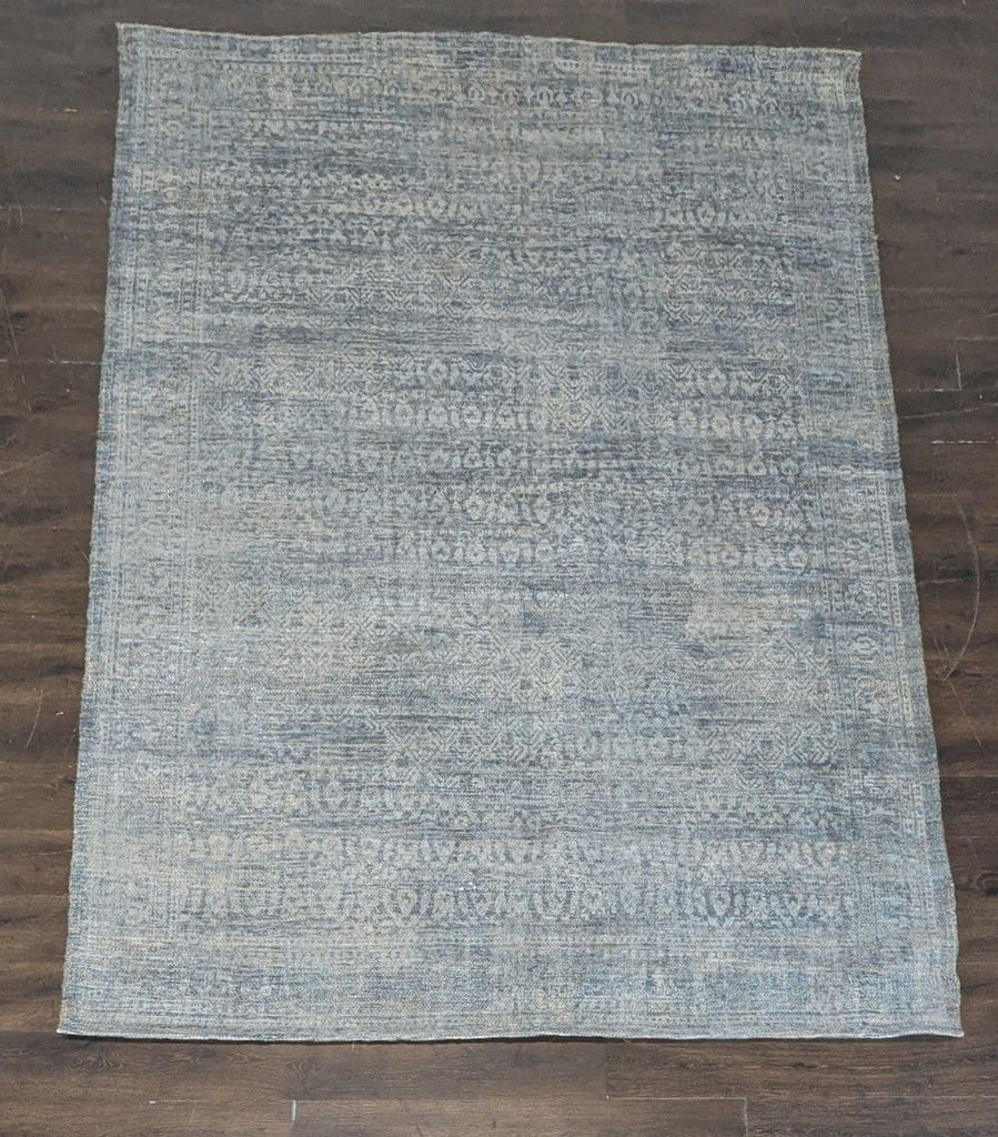 3. Overhead view of a blue West Elm rug featuring a faded geometric pattern on hardwood flooring.