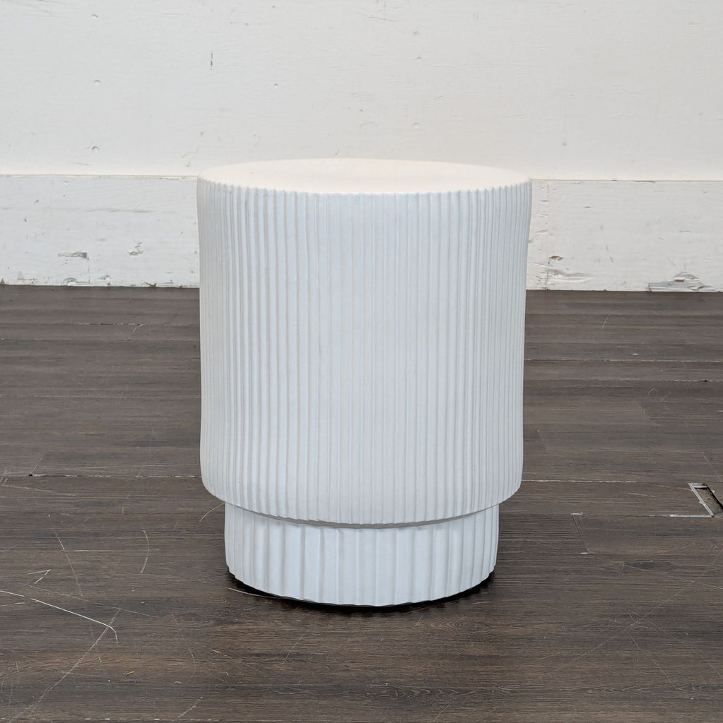 2. White ribbed West Elm end table with a rounded base, shown empty on a wooden floor against a white wall.