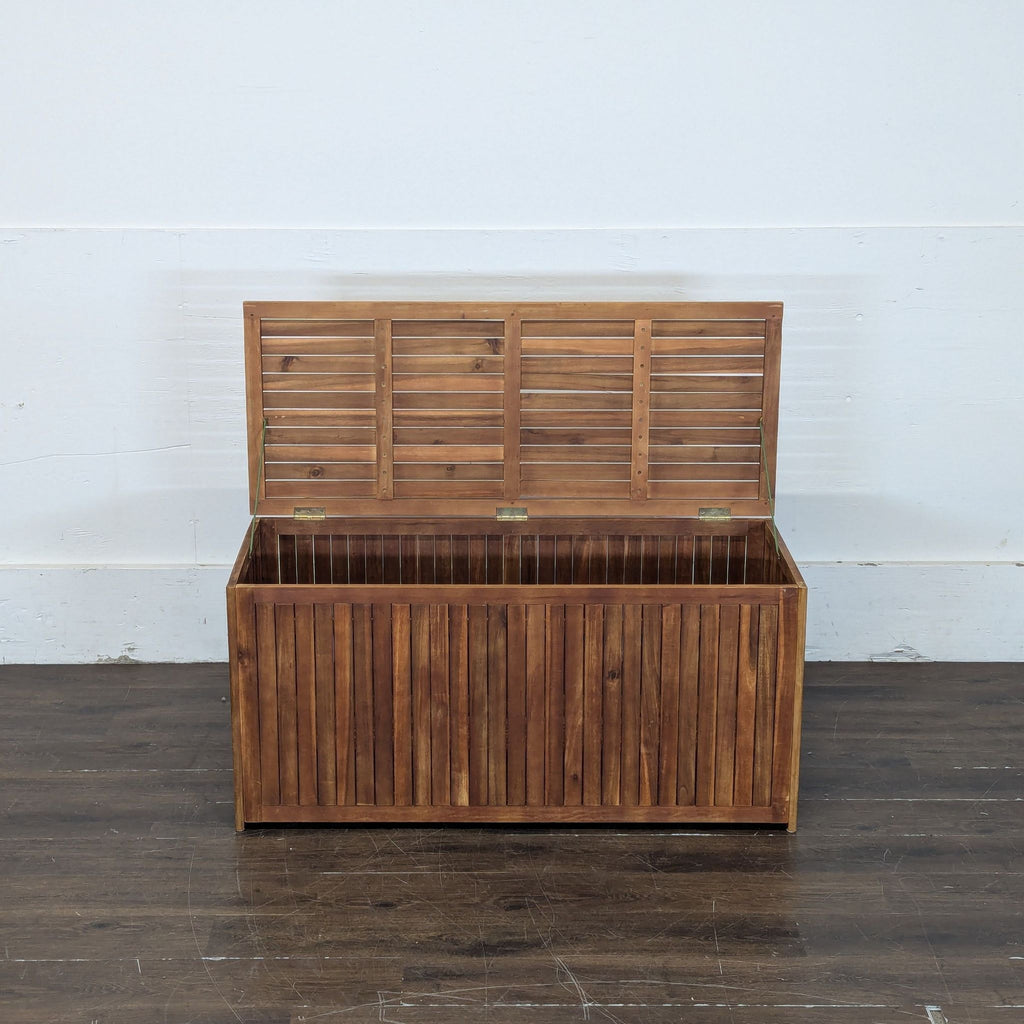 2. Wooden trunk with vertical slats shown open, revealing a spacious interior on a wooden floor.