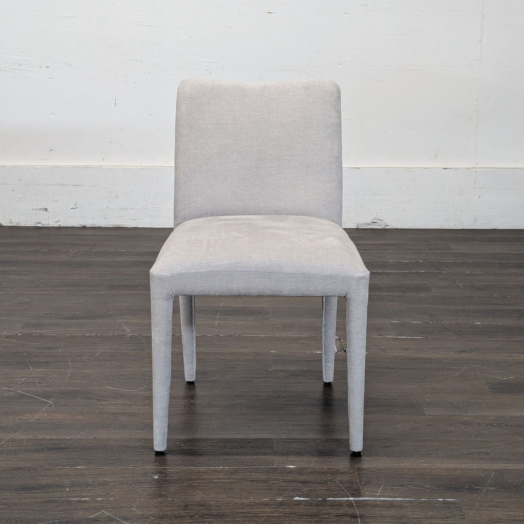 Front view of Moe's Home Collection dining chair in light grey fabric, placed on a dark wood floor.