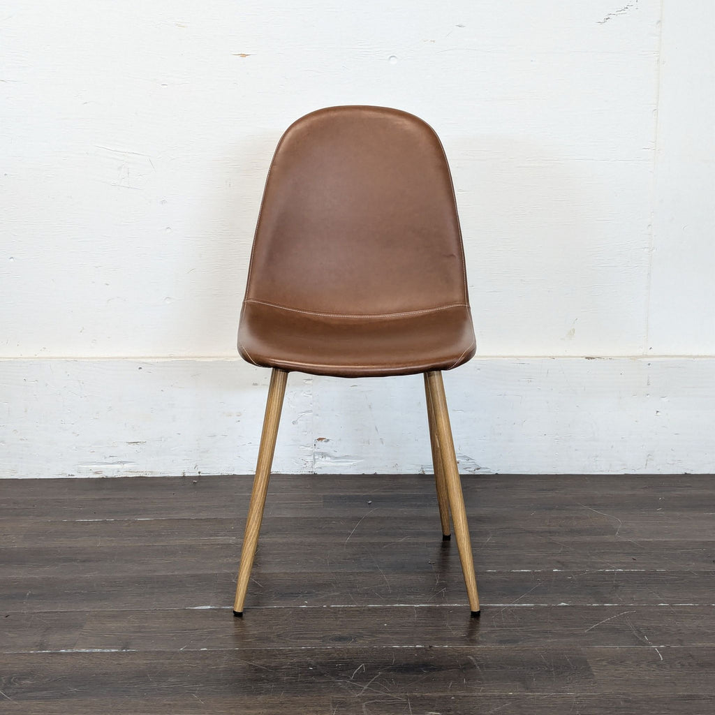 A brown dining chair with a curved back and wooden legs is placed on a dark wooden floor.  