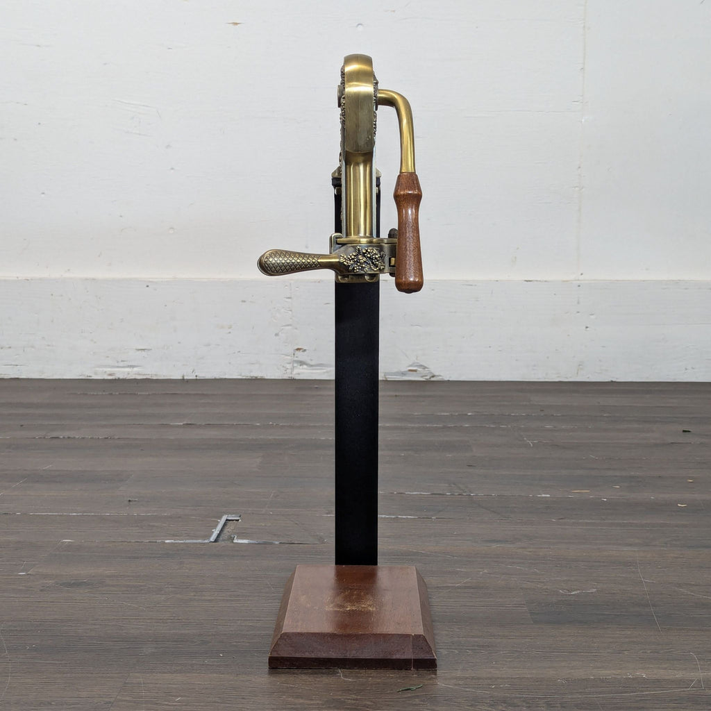 Antique brass and wood Rogar Estate lever corkscrew opener standing upright on a wooden base, side view.