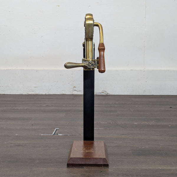 Antique brass and wood Rogar Estate lever corkscrew opener standing upright on a wooden base, side view.
