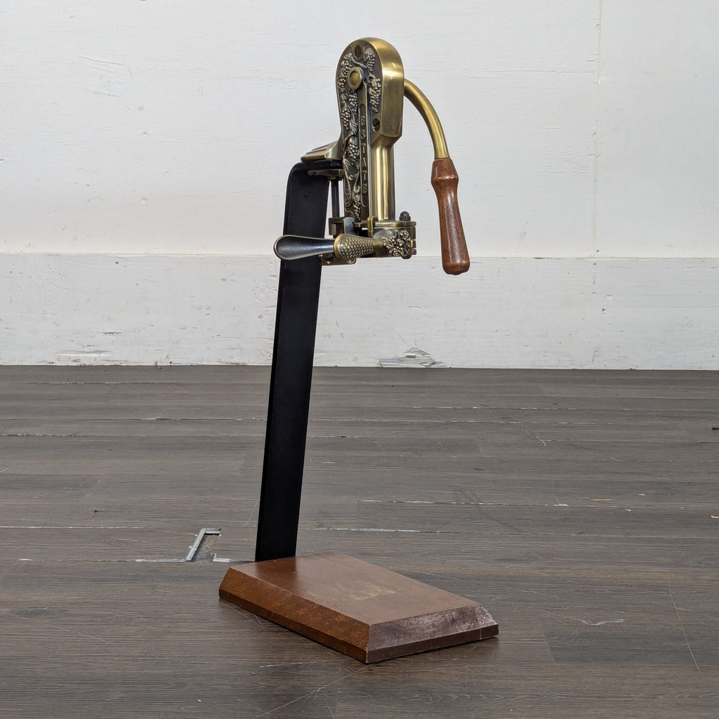 Decorative Rogar Estate tabletop wine opener with ornate brass and wood details, angled on a sturdy wood base.