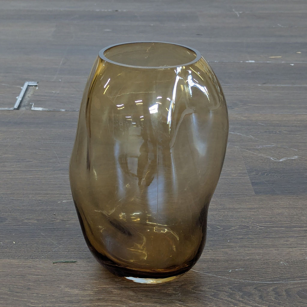 1. Irregularly shaped brown glass vase with a glossy finish, placed on a wooden floor.