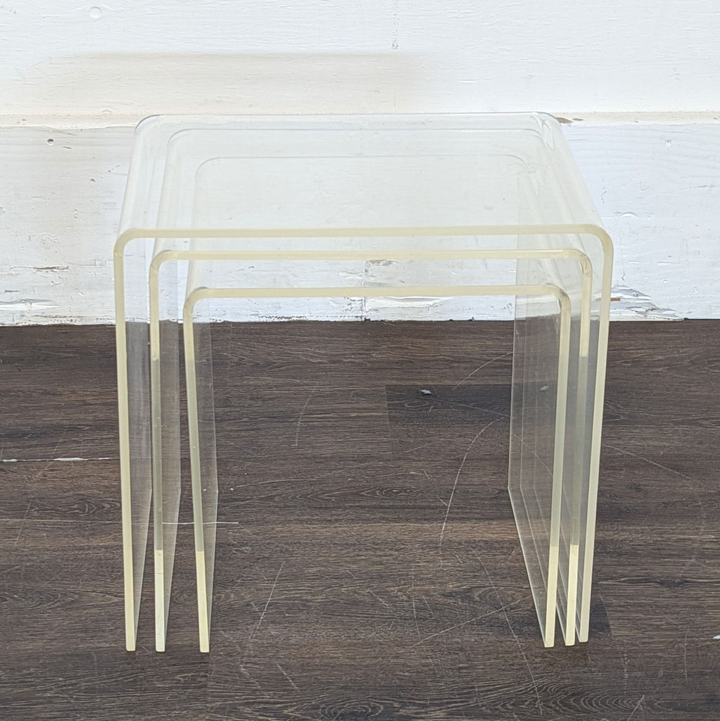 2. Modern transparent nesting end tables in acrylic, shown stacked together on a wooden floor and white background.