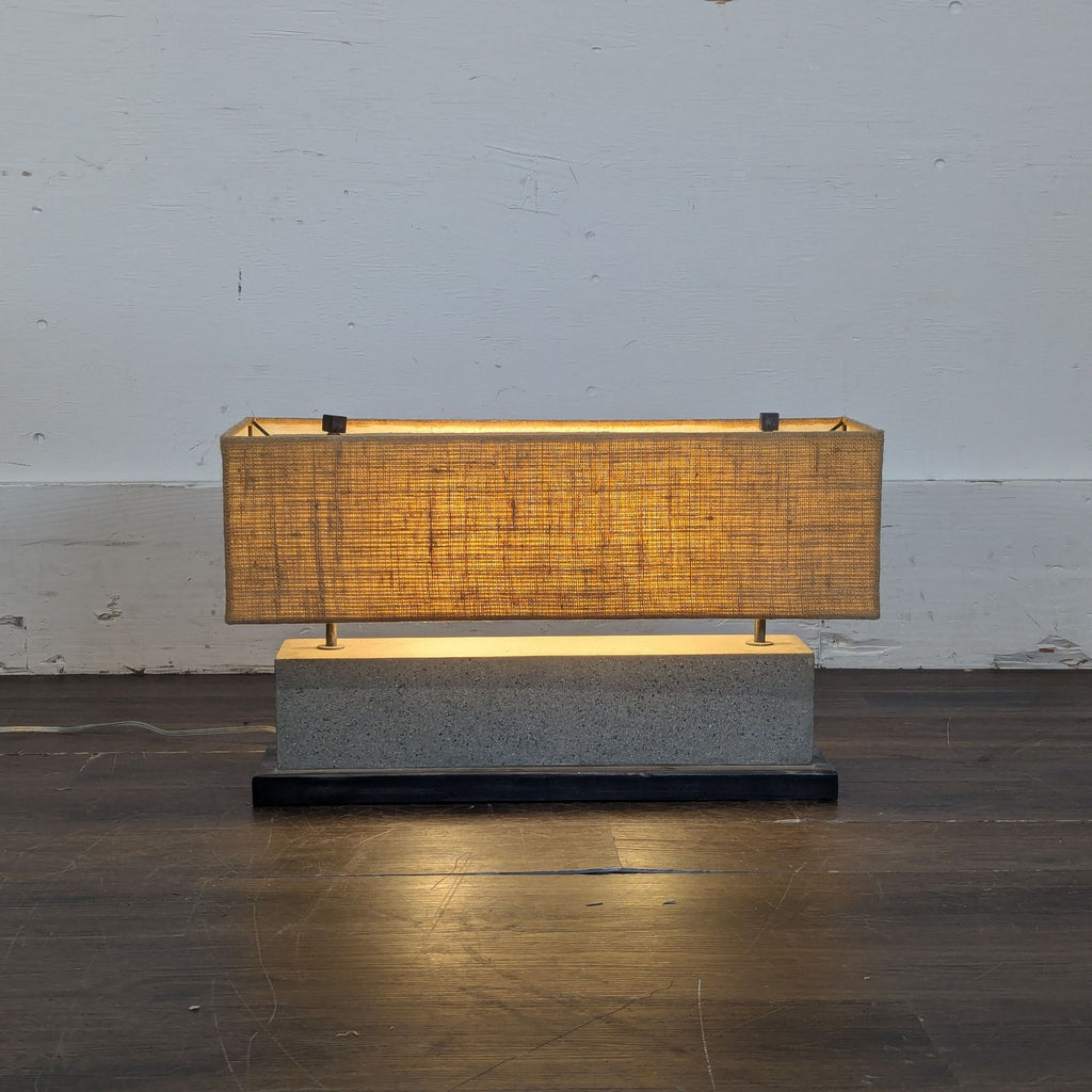 2. Crate and Barrel lamp featuring a textured rectangular fabric shade and solid stone base, illuminated on wood floor.