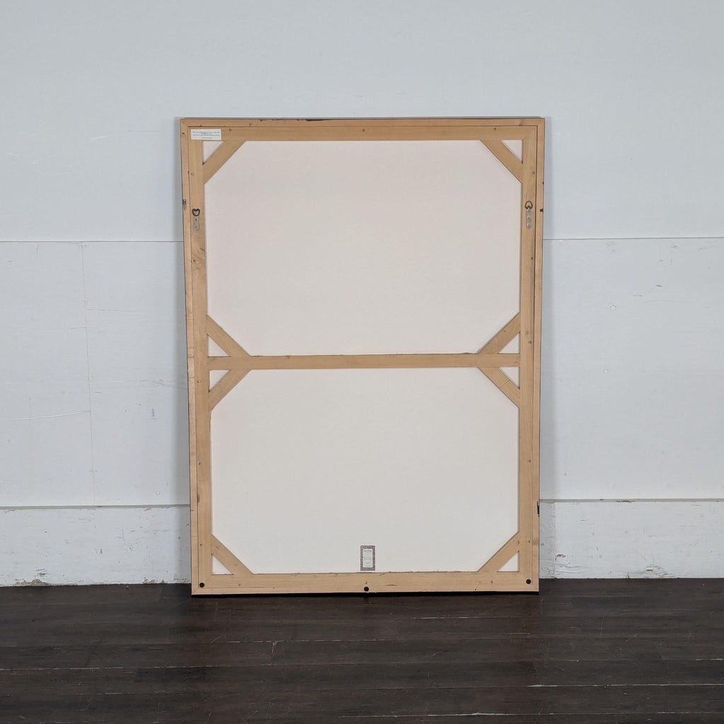 3. Back view of a large print or framed artwork with wooden stretcher bars and a white backing.