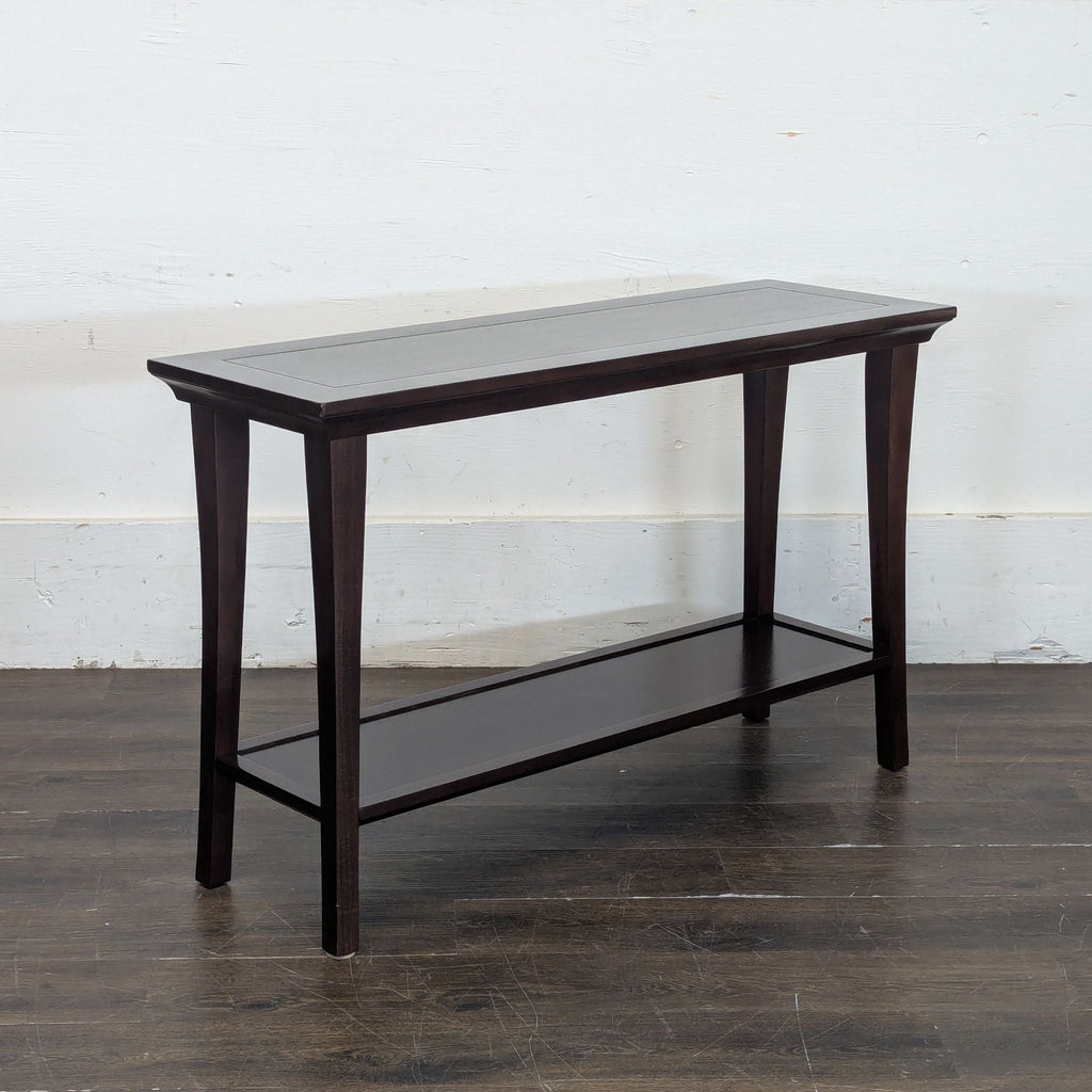 2. Angled view of a rectangular side table in dark wood, featuring a slim bottom shelf and flared legs.