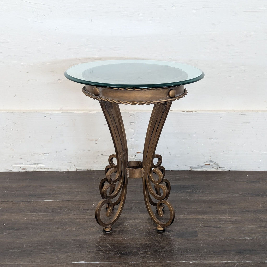 2. Elegant end table with glass top and bronze-colored, curved metal legs against a white wall.