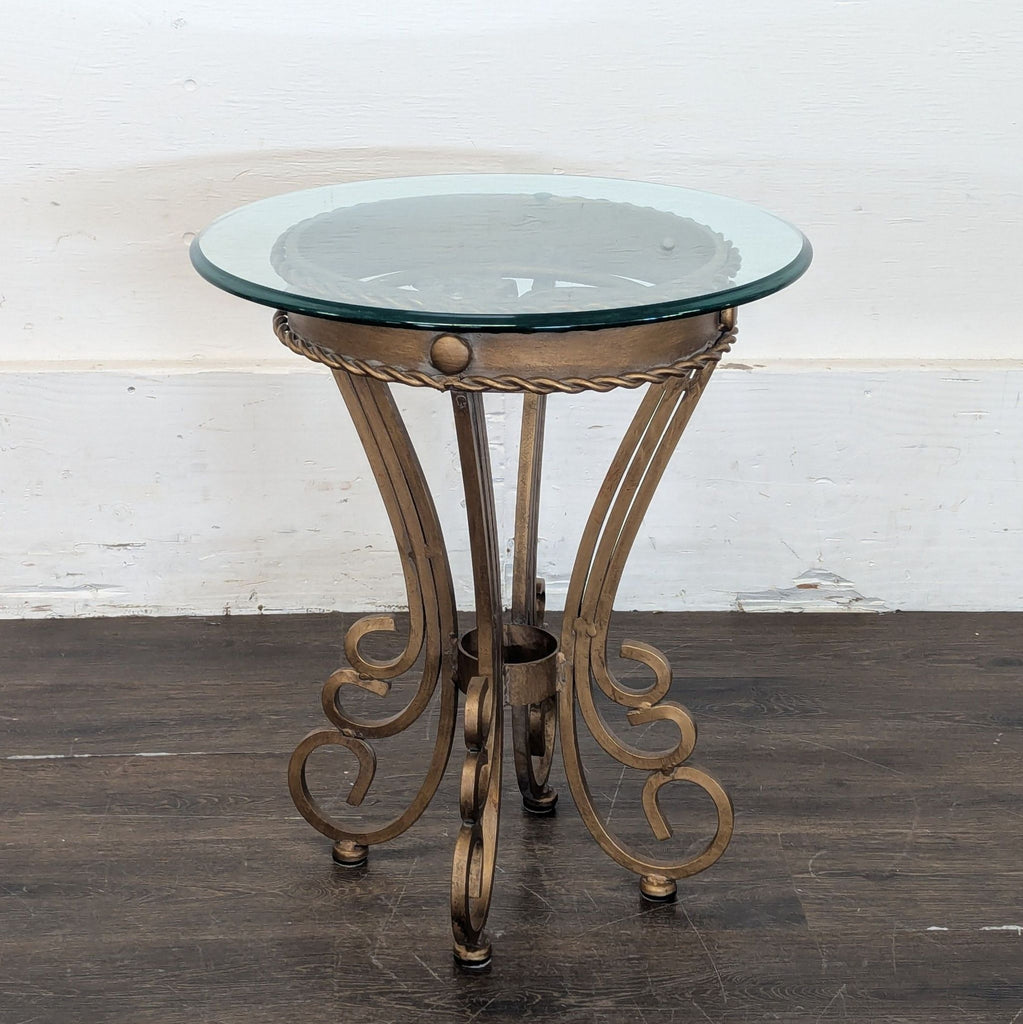 3. Stylish round end table featuring a glass top and decorative scrollwork metal base on dark wood floor.