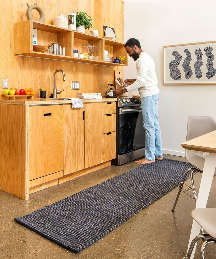 a man standing in a kitchen next to a stove.