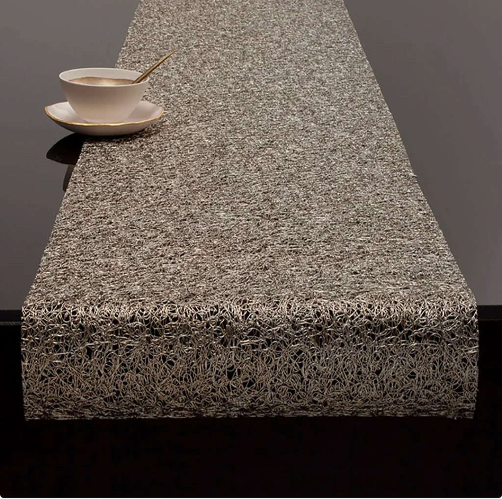 Refined metallic lace textile from Chilewich, featuring open netting, used as a modern table runner.
