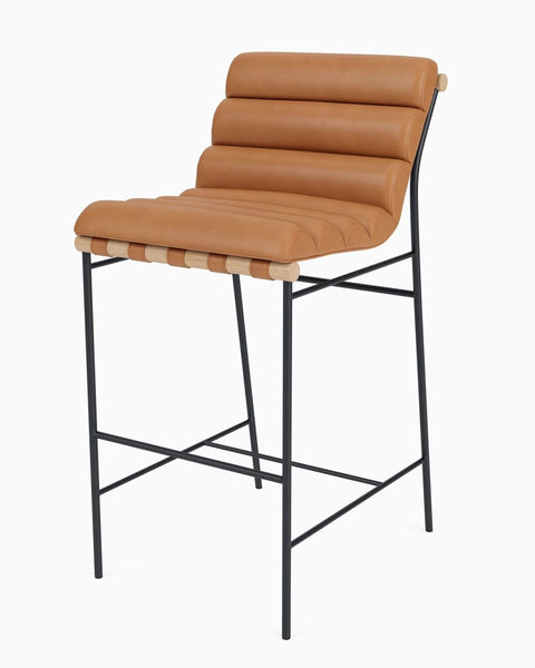 Tan leather bar stool by Reperch with ribbed cushioning, black metal legs, and wood accents, angled side view.