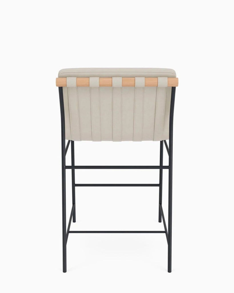 3. Back view of a beige upholstered stool with visible wood trim and black metal base structure.