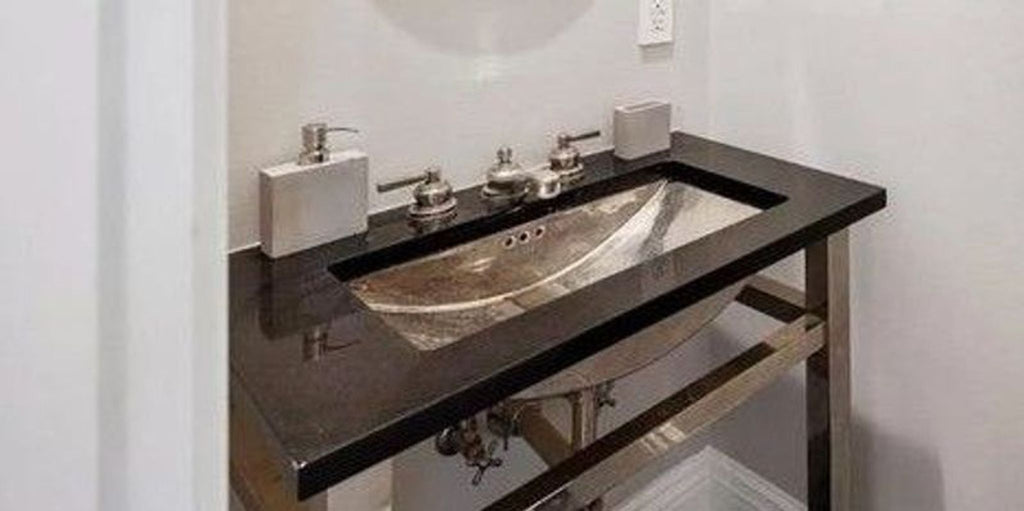 Waterworks bathroom sink featuring a hammered nickel basin, black stone backplate, and full faucet set.