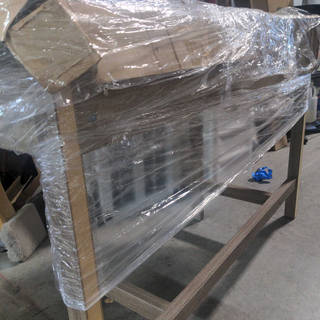 2. Side & Console Table partially visible through clear stretch wrap and cardboard packaging in a warehouse.