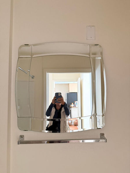 1. Ikea wall-mounted square mirror with rounded edges and a metal towel bar, reflecting a person taking a photo.