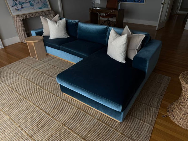 1. Interior Define sectional sofa in blue velvet with chaise, shown in a cozy living room with pillows and neutral decor.
