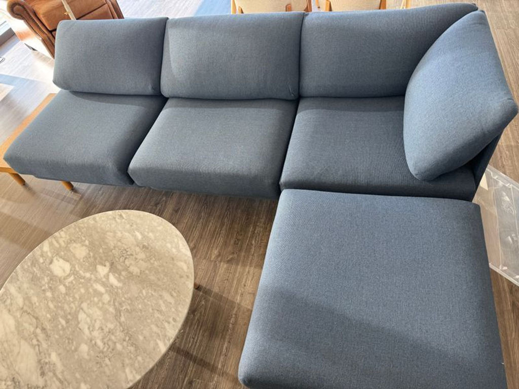 1. Overhead view of a Burrow sectional sofa in navy blue with chaise lounge and a nearby marble coffee table.