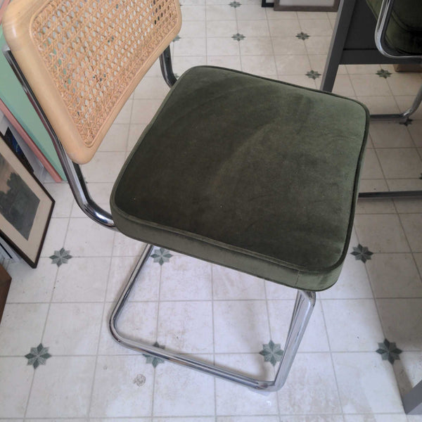 1. Chair with a green cushion seat, chrome cantilever legs, and a woven rattan backrest on tiled floor.