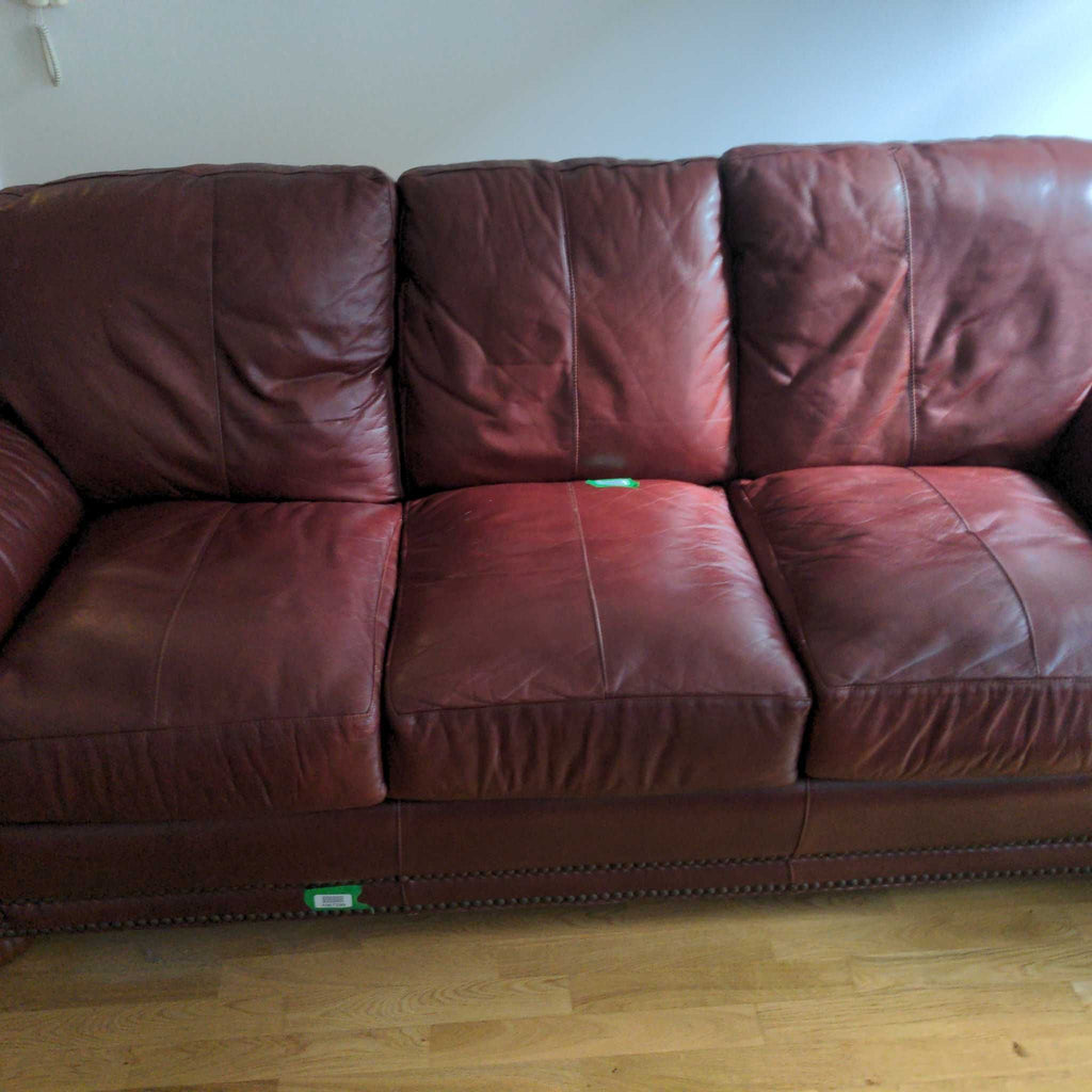 2. Close-up of a maroon Reperch 3-seat leather sofa showing cushioned seats and textured upholstery details.  