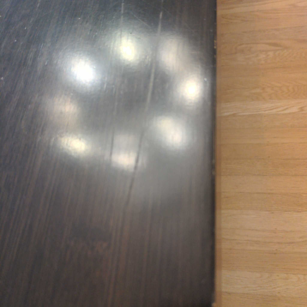 2. Room and Board dining table with visible surface scratches and light reflections on the dark tabletop.