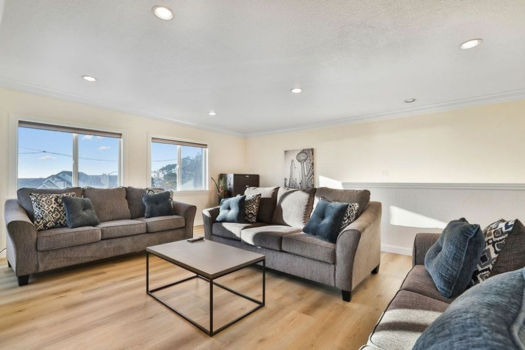 1. Rectangular coffee table with a metal frame and wood top is centered in a modern living room with gray sofas.