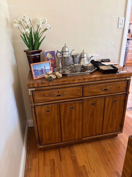 1. Drexel sideboard with decorative items on top, including a flower vase and silver tea set, against a beige wall.