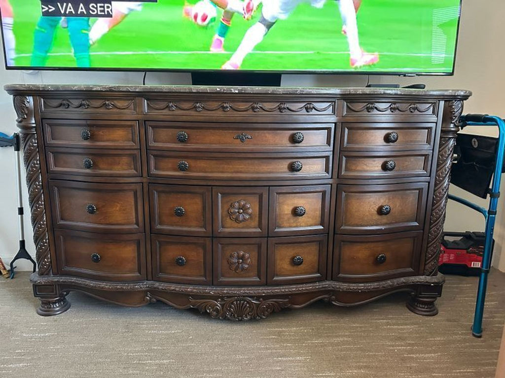 2. Ashley Furniture dresser in rich wood with multiple drawers, elegant carvings, and a marble top, front view.  