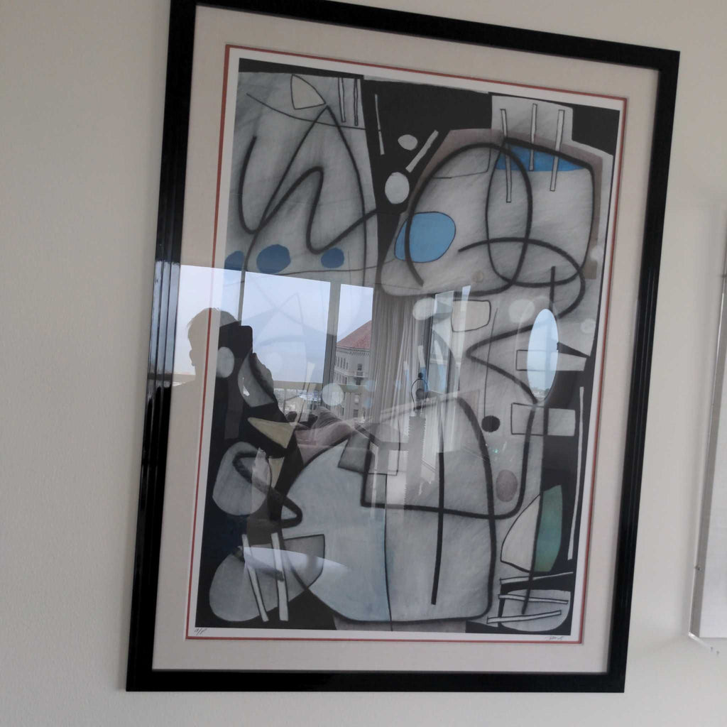 1. Framed abstract print with geometric shapes and blue accents, photographed with glass reflection visible.