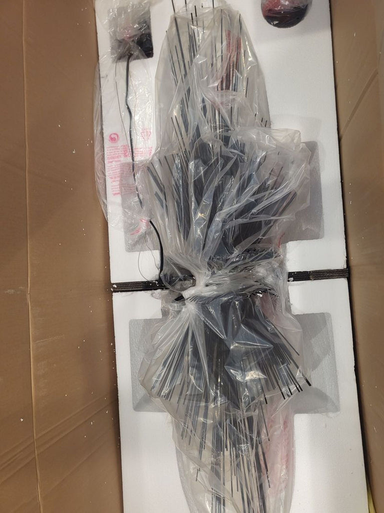 A Visual Comfort Ishtar chandelier with radiating quills, packaged in a box and covered in protective plastic.