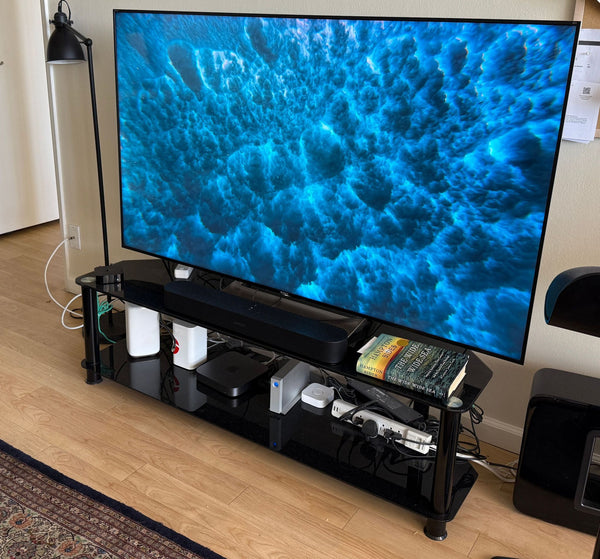 1. Sony TV on a black stand, displaying vivid ocean imagery, with books and electronics organized below.