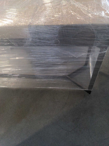 1. Crate and Barrel side or console table partially wrapped in plastic, showing sleek metal legs and modern design.  