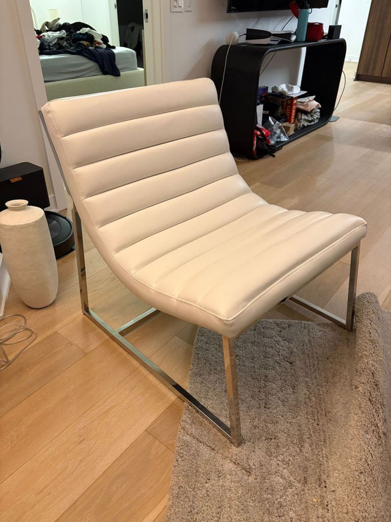 2. Sleek Noble House white lounge chair with channel stitching and polished metal frame, placed on light hardwood floors.