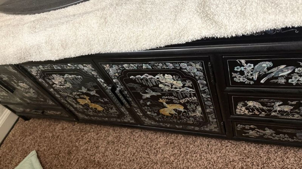 Ornate dresser with detailed Asian motifs inlaid in mother of pearl on black finish, combining beauty and function.
