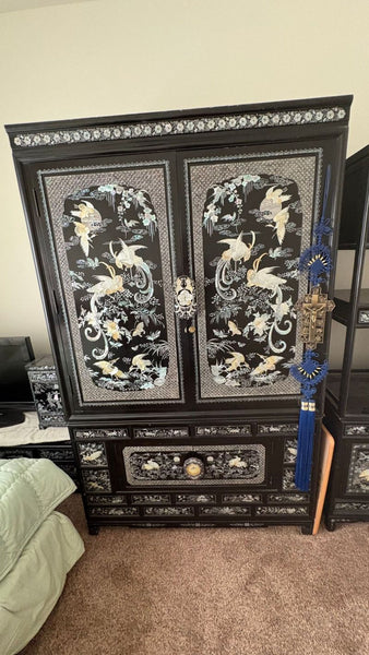 Elegant black cabinet with mother of pearl inlay, featuring crane and floral designs, with drawers and storage.