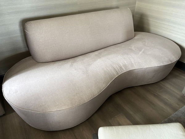 Curved bean-shaped beige lounge sofa with plush upholstery, adding modern style to living spaces.