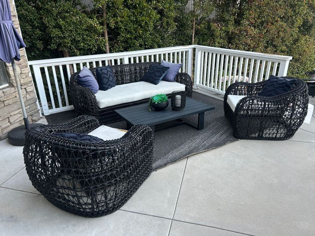 Wicker outdoor set with sofa, two chairs, table, and cushions, ideal for patio or garden relaxation.