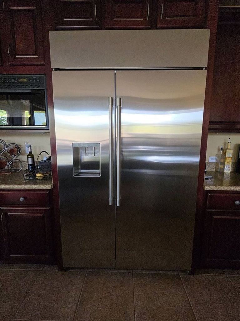 Stainless steel GE Monogram fridge, featuring clean interior, side-by-side doors, and external ice dispenser.