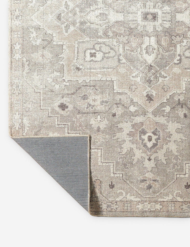 a grey rug with a beige and white design.